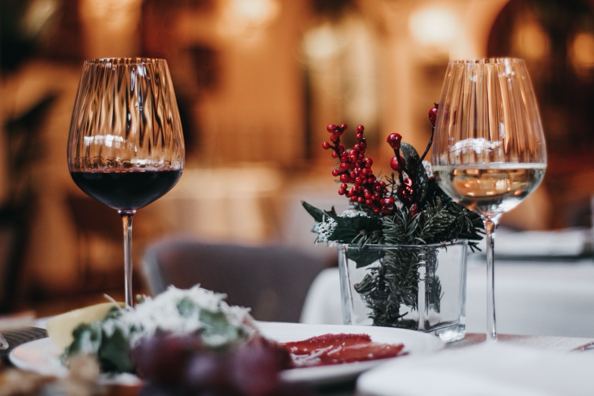 Deux verres de vin et une petite décoration de houx sur une table de restaurant